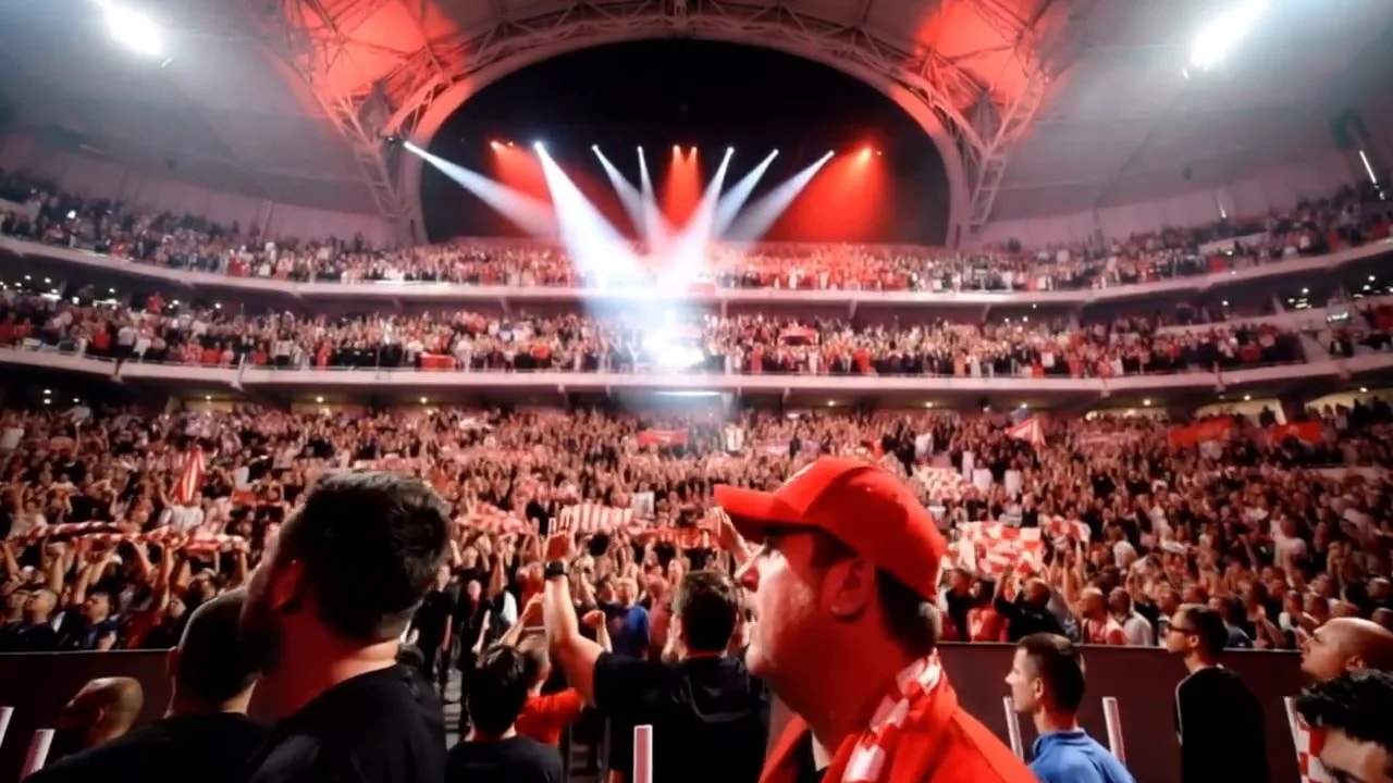 Crowd and supporters inside a brightly lit football stadium with an illuminated tunnel